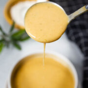 Brown butter gravy pouring off a ladle into a bowl.