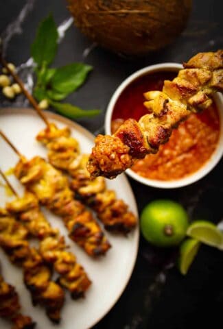 Charcoal chicken satays dipped in peanut sauce.