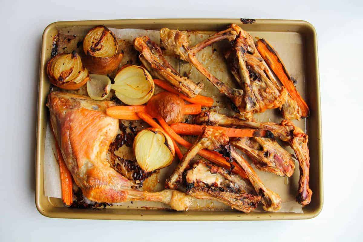 The roasted chicken bones and vegetables on a tray.