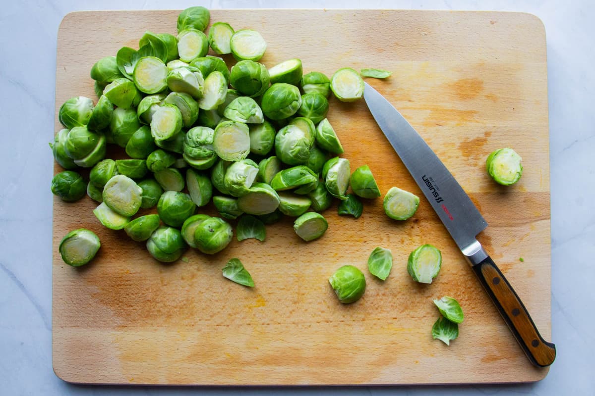 Cutting the brussel sprouts on a wooden board.