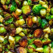 A close up shot of crispy roasted Brussel sprouts with banana and lime in a cast iron pan.