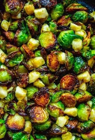 A close up shot of crispy roasted Brussel sprouts with banana and lime in a cast iron pan.