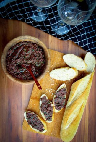 Olive tapenade in a bowl with a french baguette on the side.