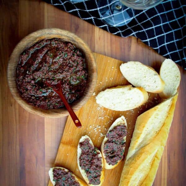 Olive tapenade in a bowl with a french baguette on the side.