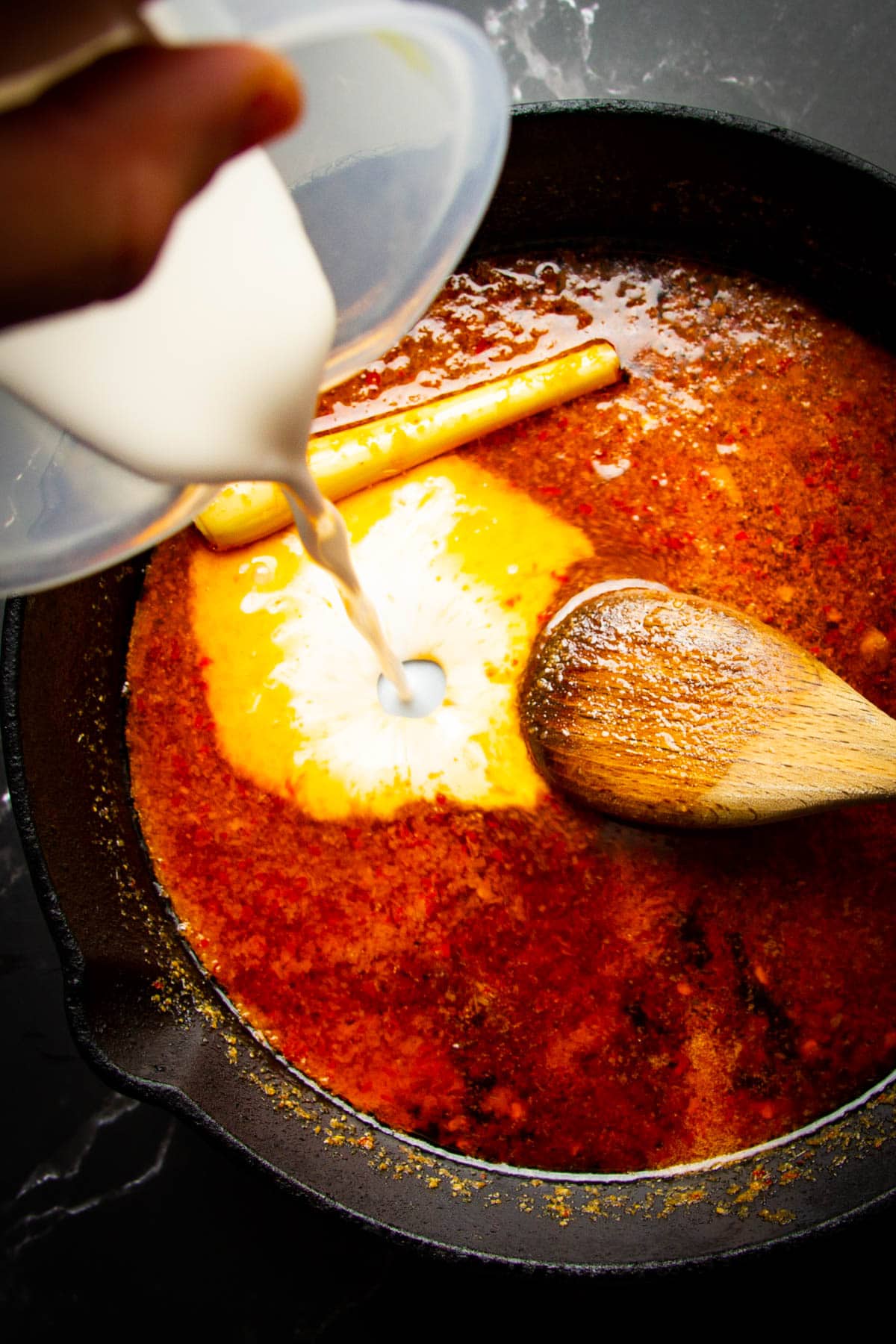 Pouring the coconut milk into the peanut sauce.