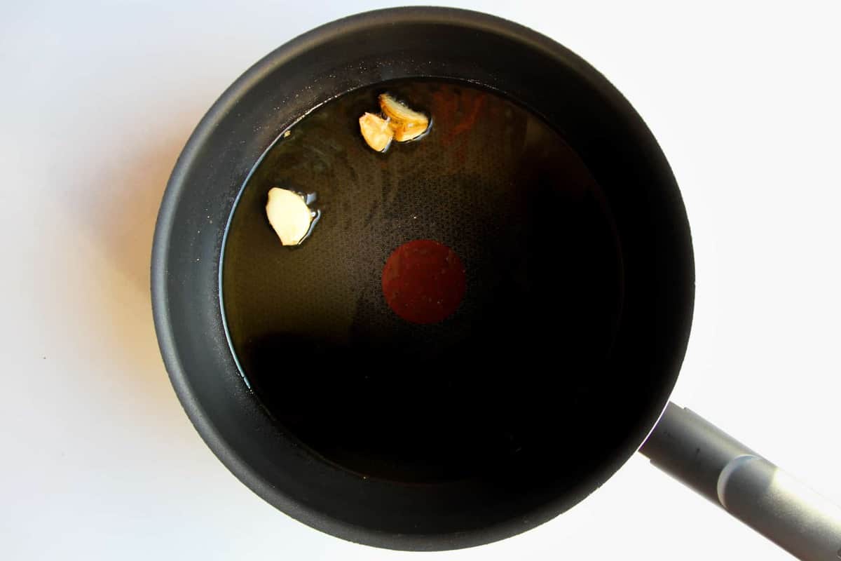 Adding the garlic to the oil in a pan.