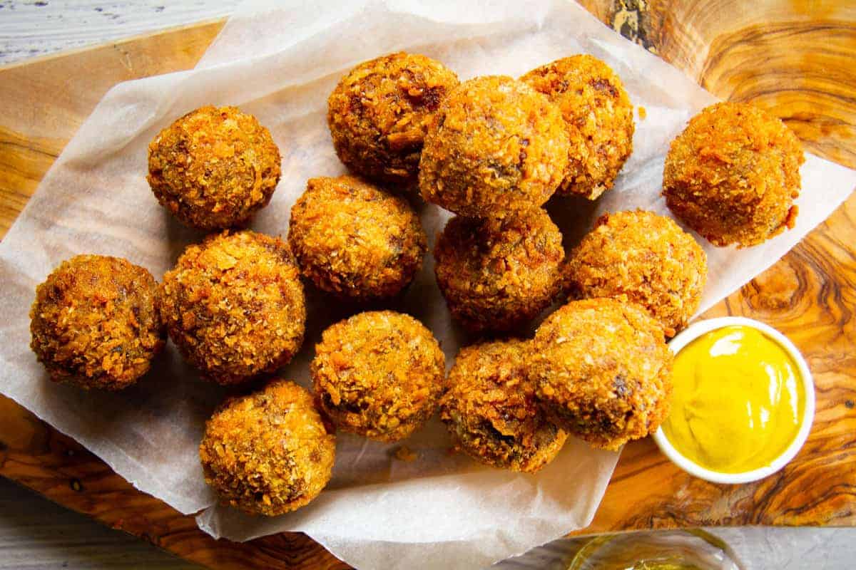 Bitterballen on a board with a mustard on the side for dipping.