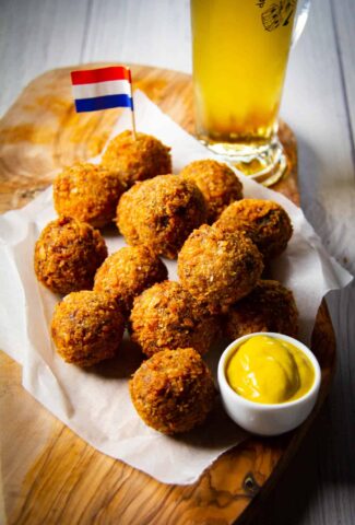 Bitterballen on a board with mustard, a Dutch flag and a cold beer.