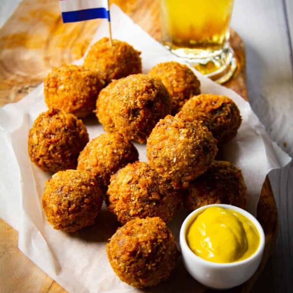 Bitterballen on a board with mustard, a Dutch flag and a cold beer.