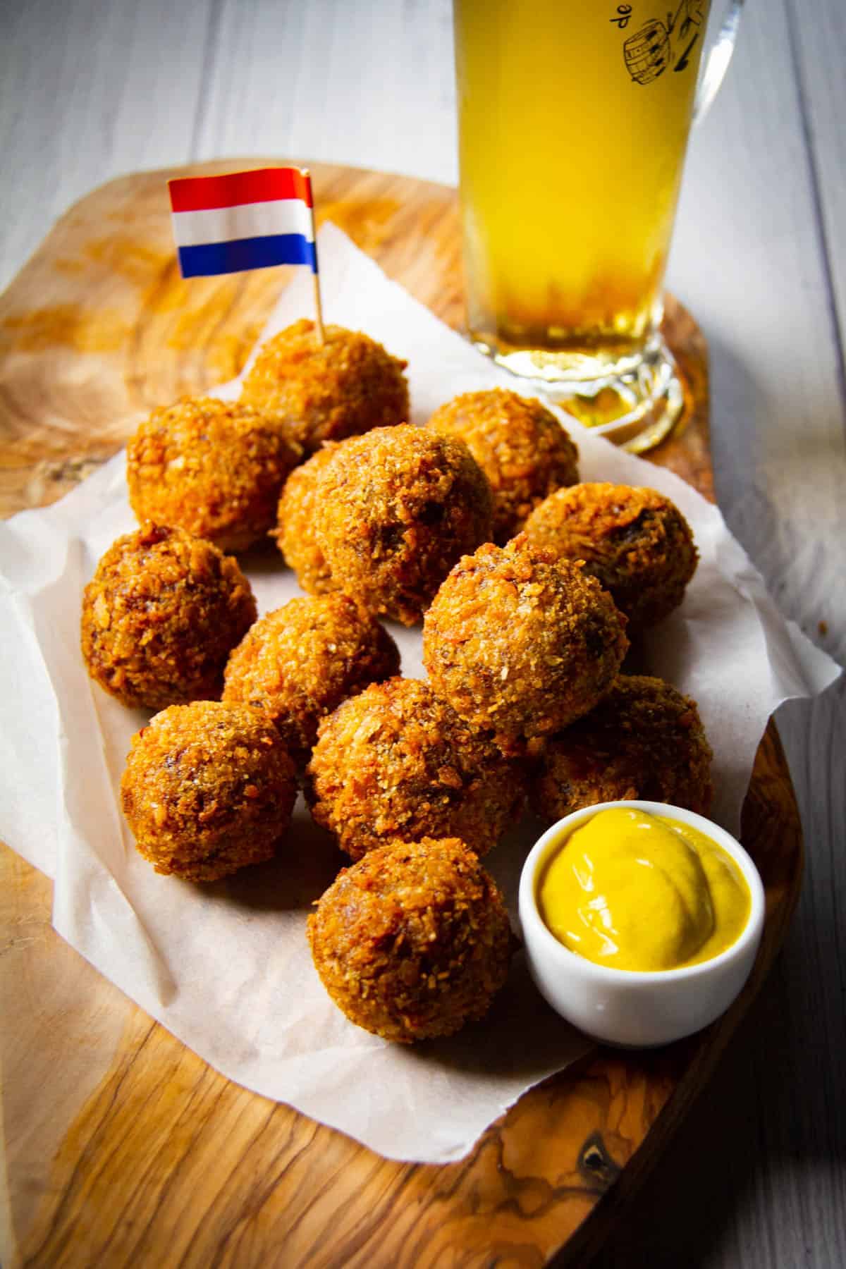 Bitterballen on a board with mustard, a Dutch flag and a cold beer.