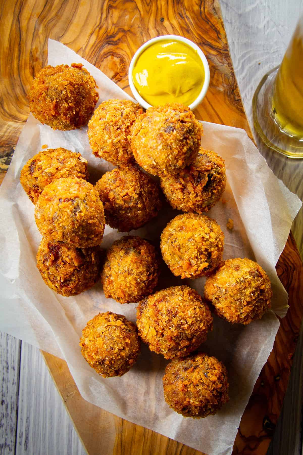 Bitterballen on a board with a mustard on the side for dipping.