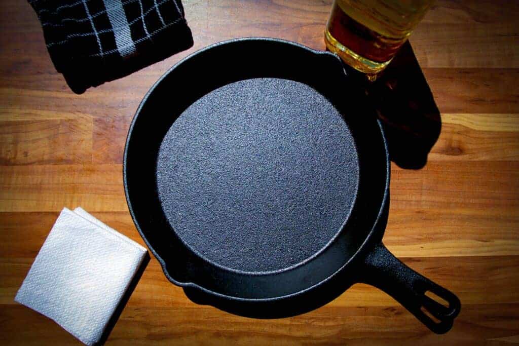 A cast iron pan with oil and a paper towel on the side.