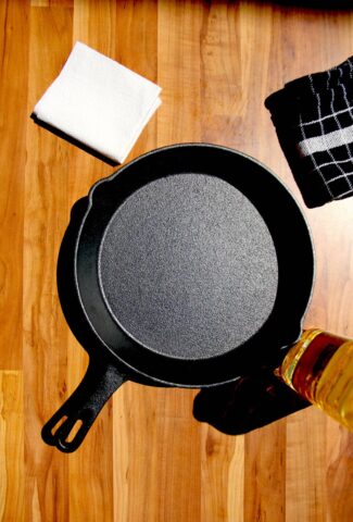 A cast iron pan on a table with oil on the side.