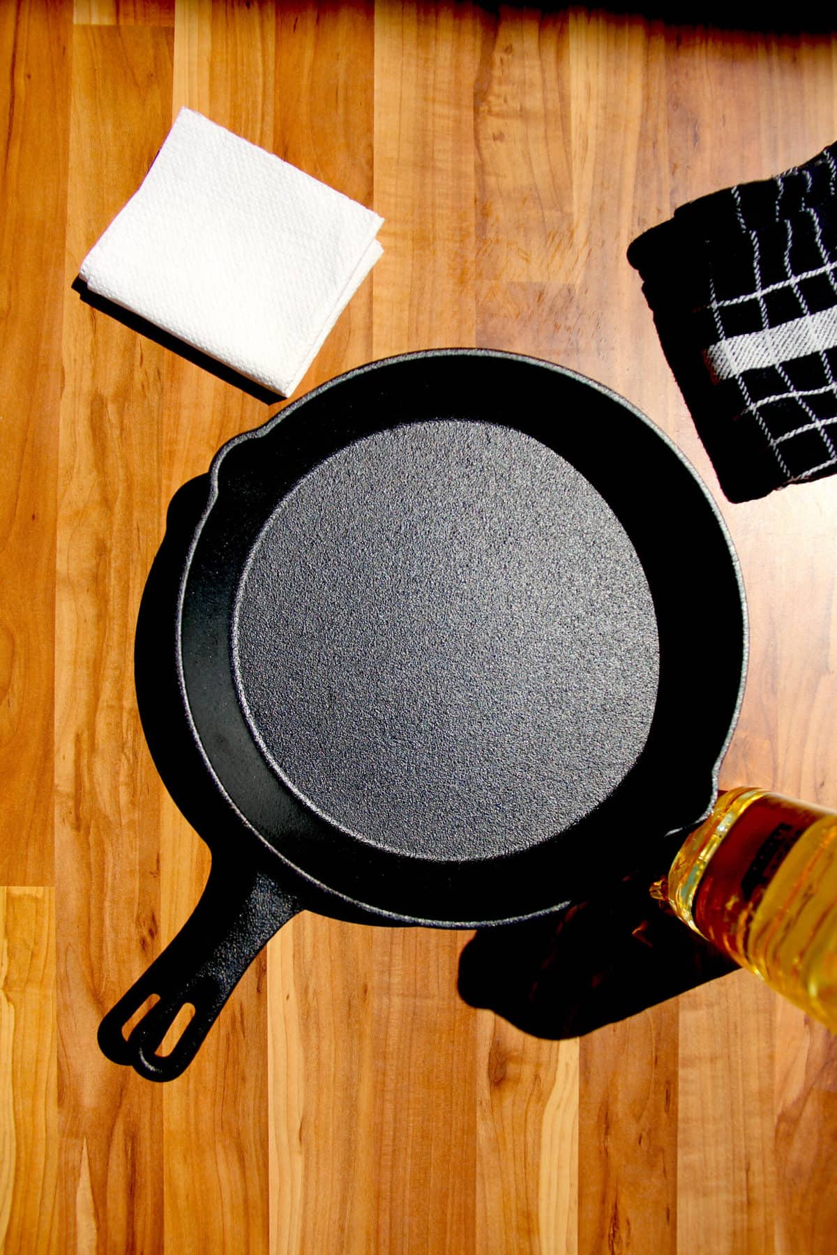 A cast iron pan on a table with oil on the side.