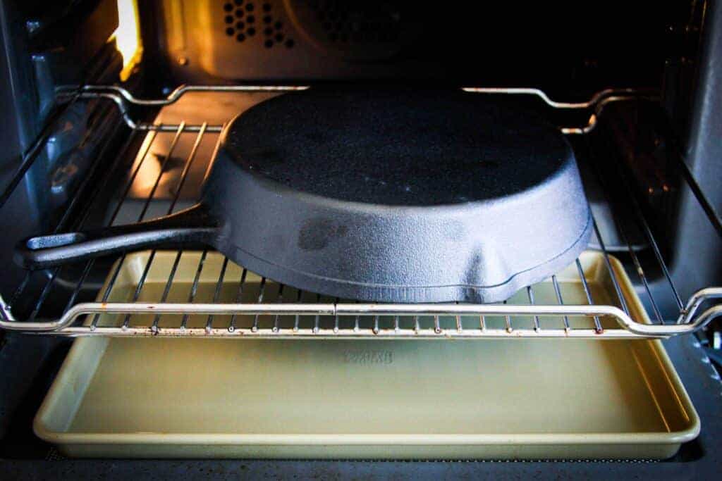 Putting the pan in the oven with a tray underneath.