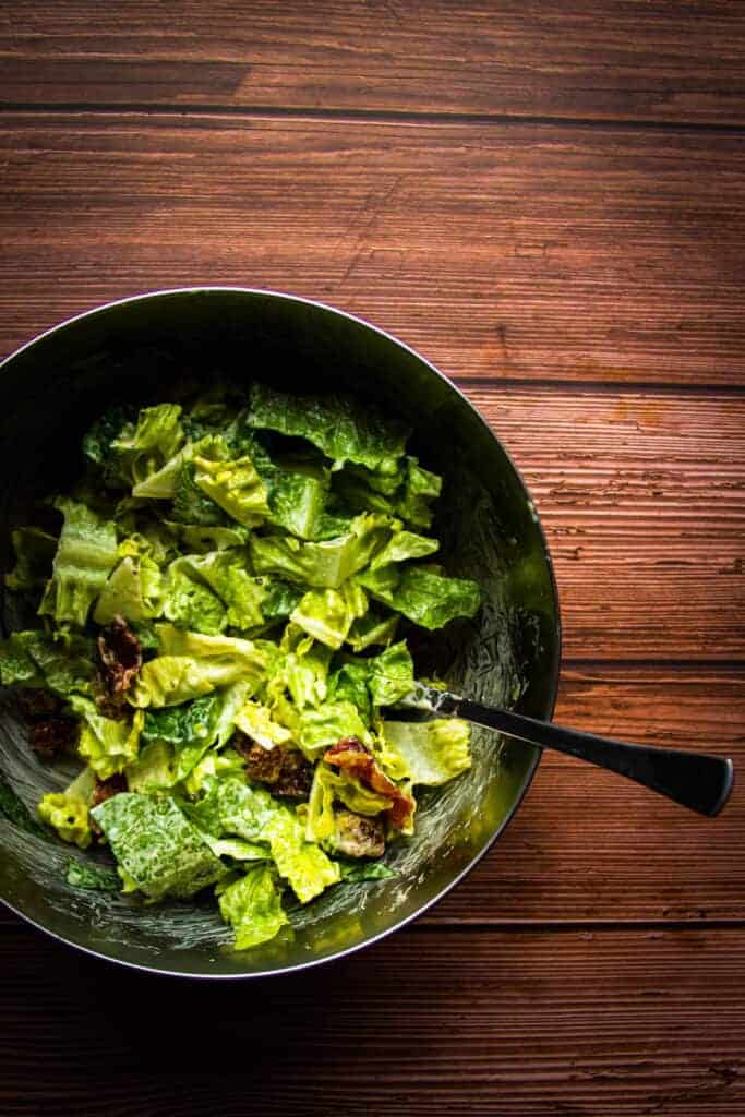 caesar salad in a bowl being mixed.