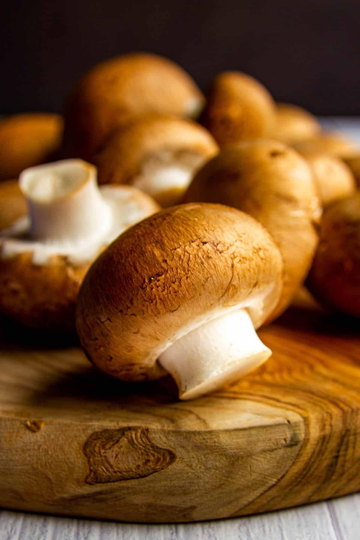 A close up picture of a chestnut mushroom on a wooden board.