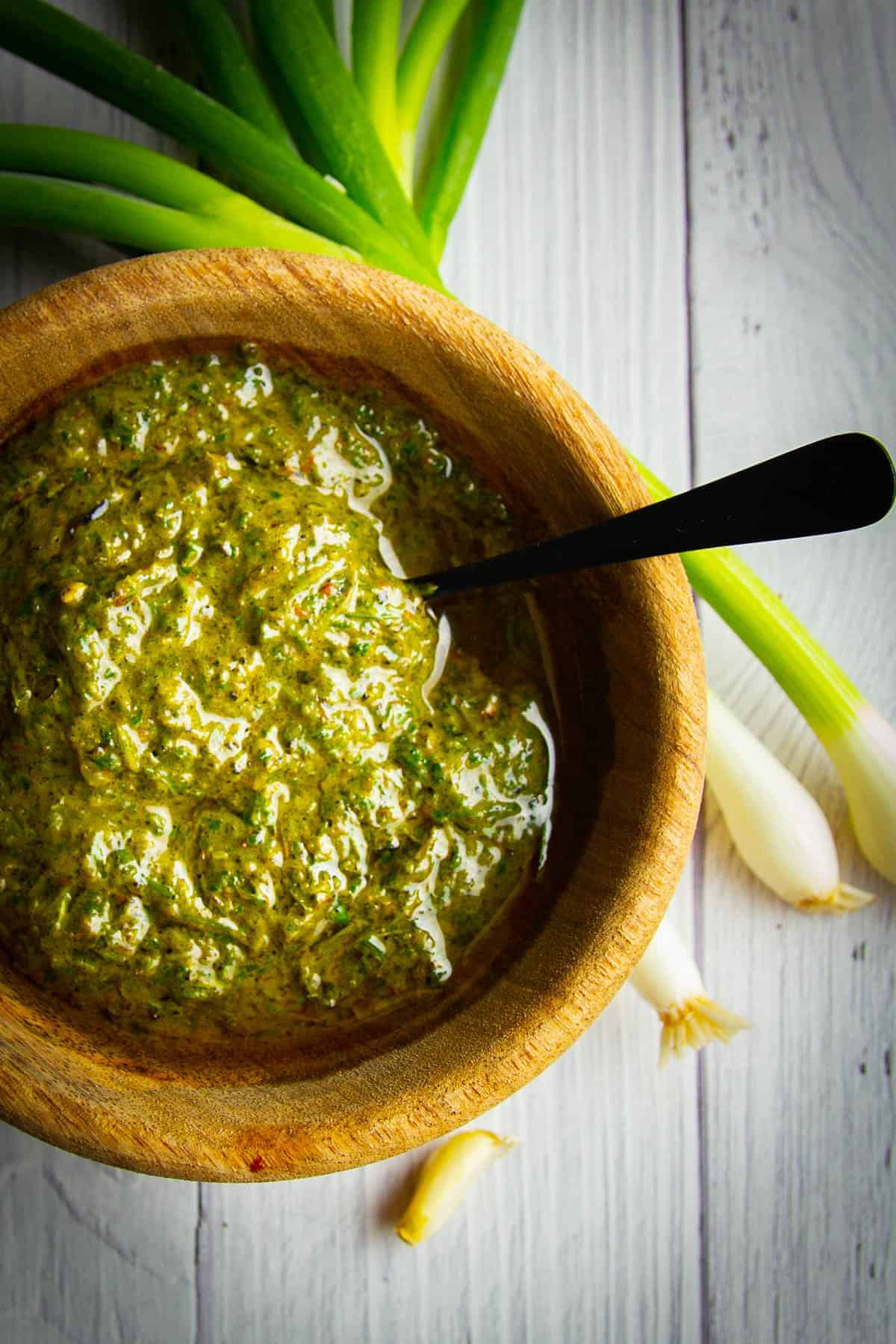 Green onion chimichurri in a bowl with green onions on the side.