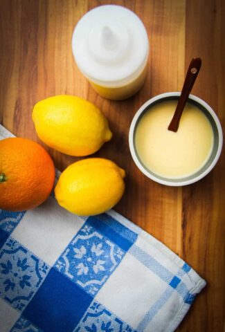 lemon vinaigrette in a bowl with some lemons and oranges.