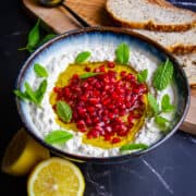 Mutabal in a bowl with lemons and fresh mint on the side.