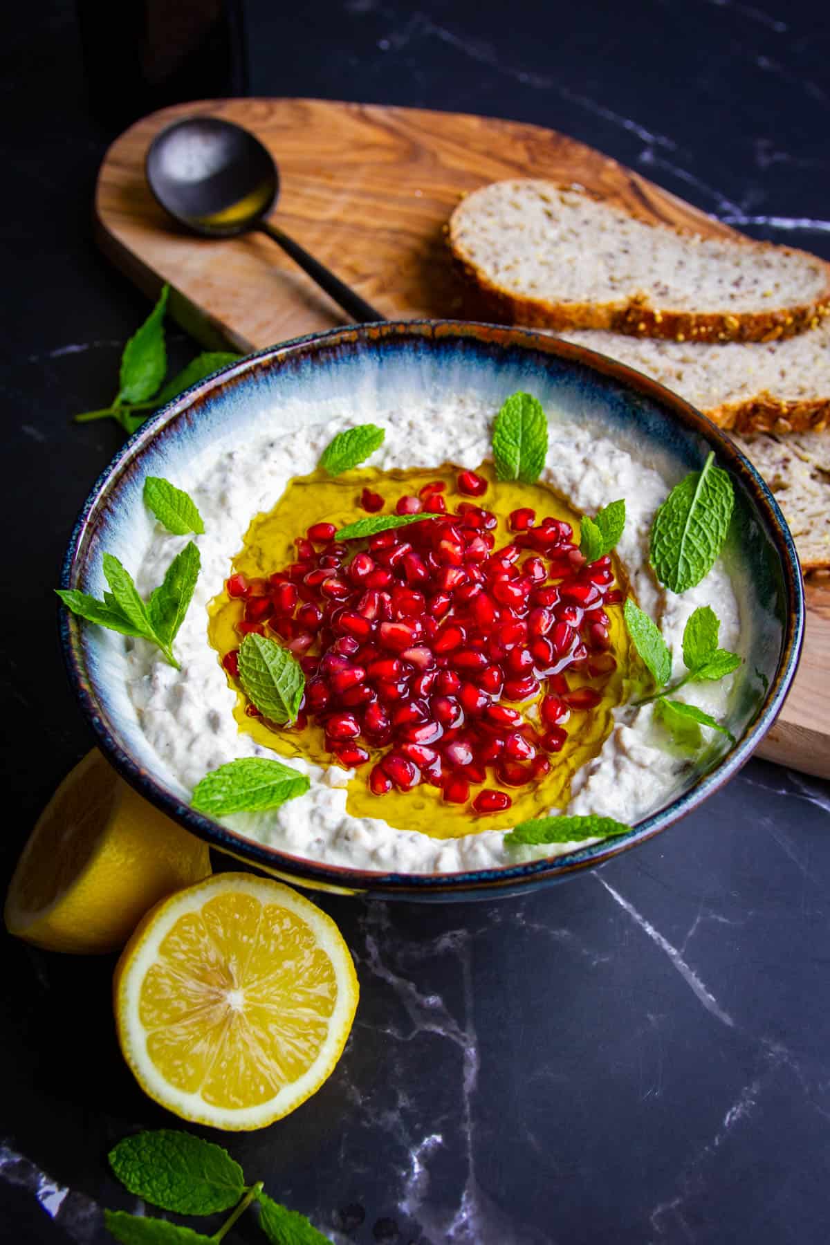 Mutabal in a bowl with lemons and fresh mint on the side.