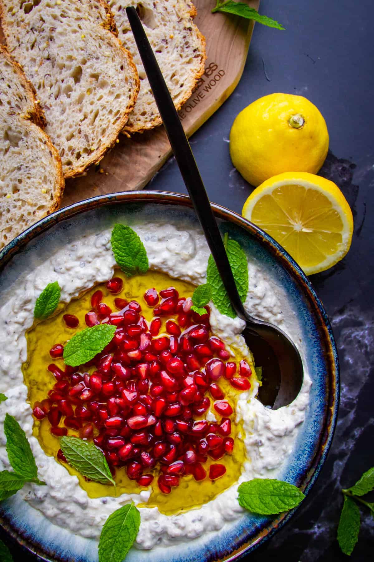 Mutabal in a bowl with lemons and fresh mint on the side.