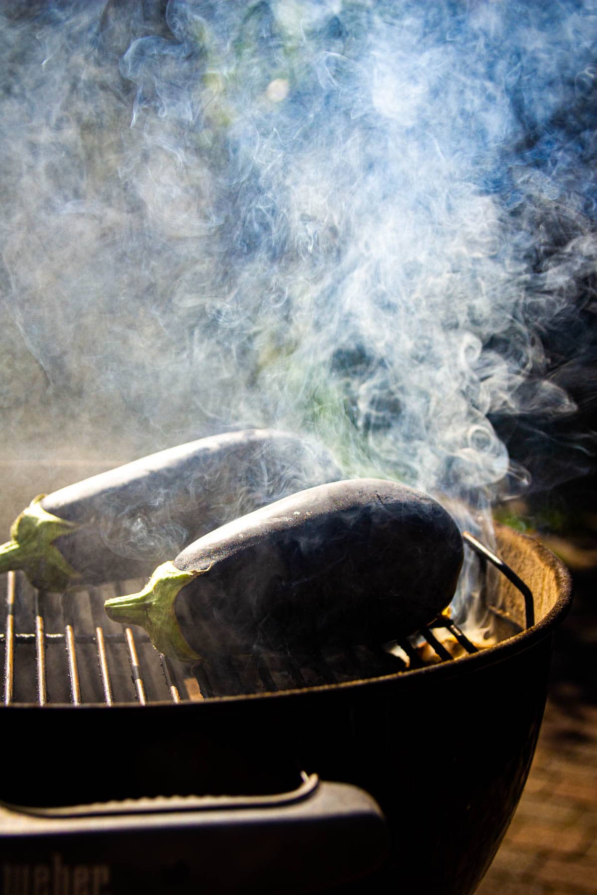 Eggplants smoking on the charcoal grill.