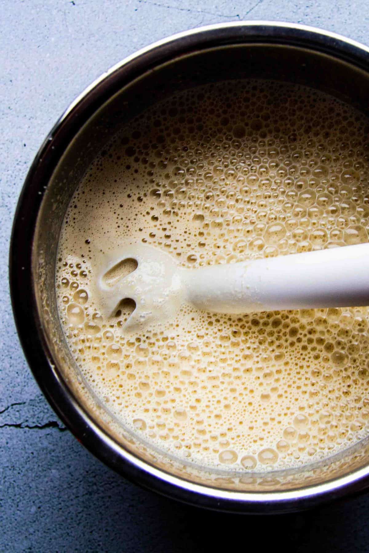 Blending the oat milk eggnog with the hand blender.