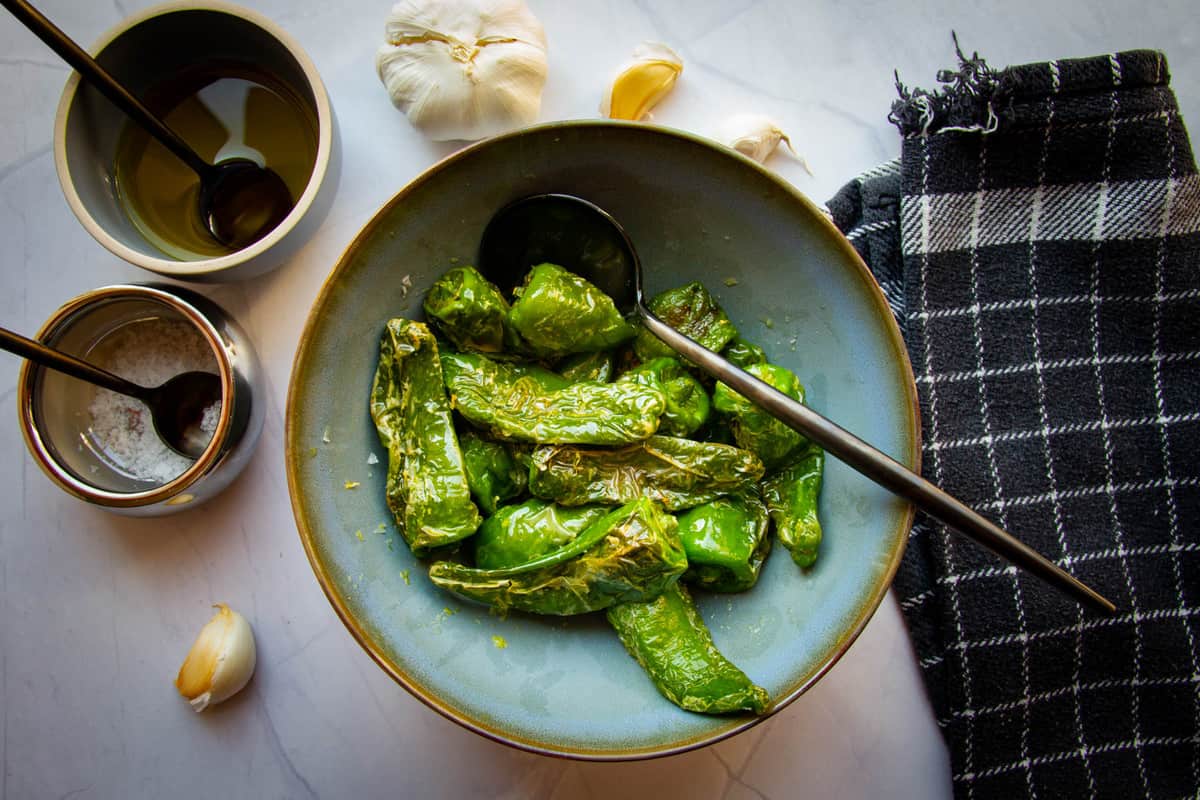 Padron peppers in a bowl with ginger garlic and lime zest.