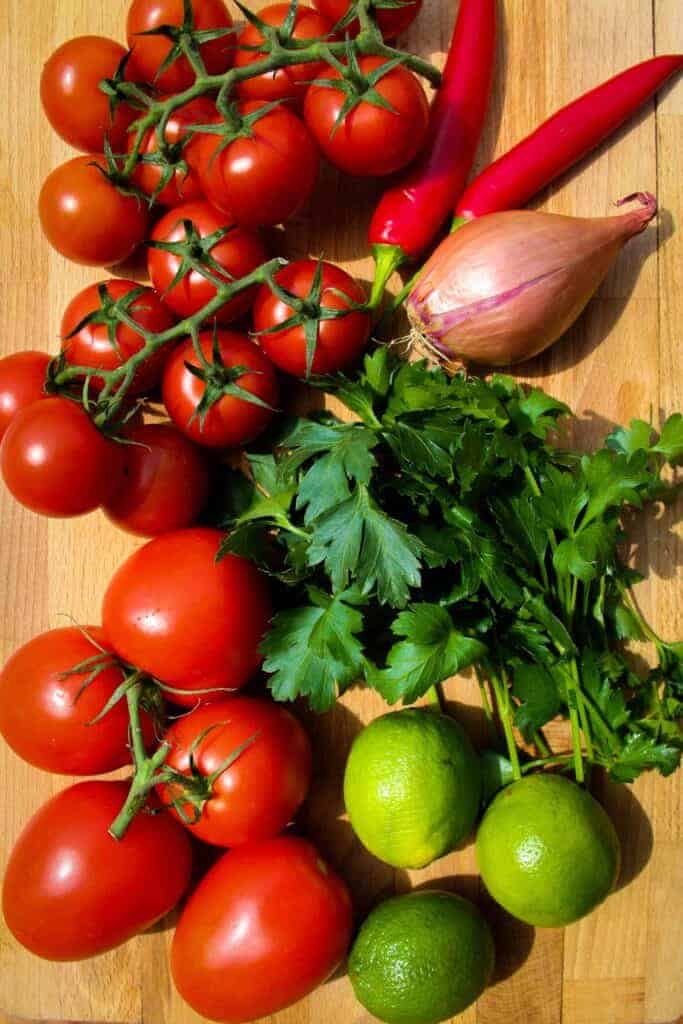 Fresh tomatoes, limes, shallot, parsley and lime on the table.