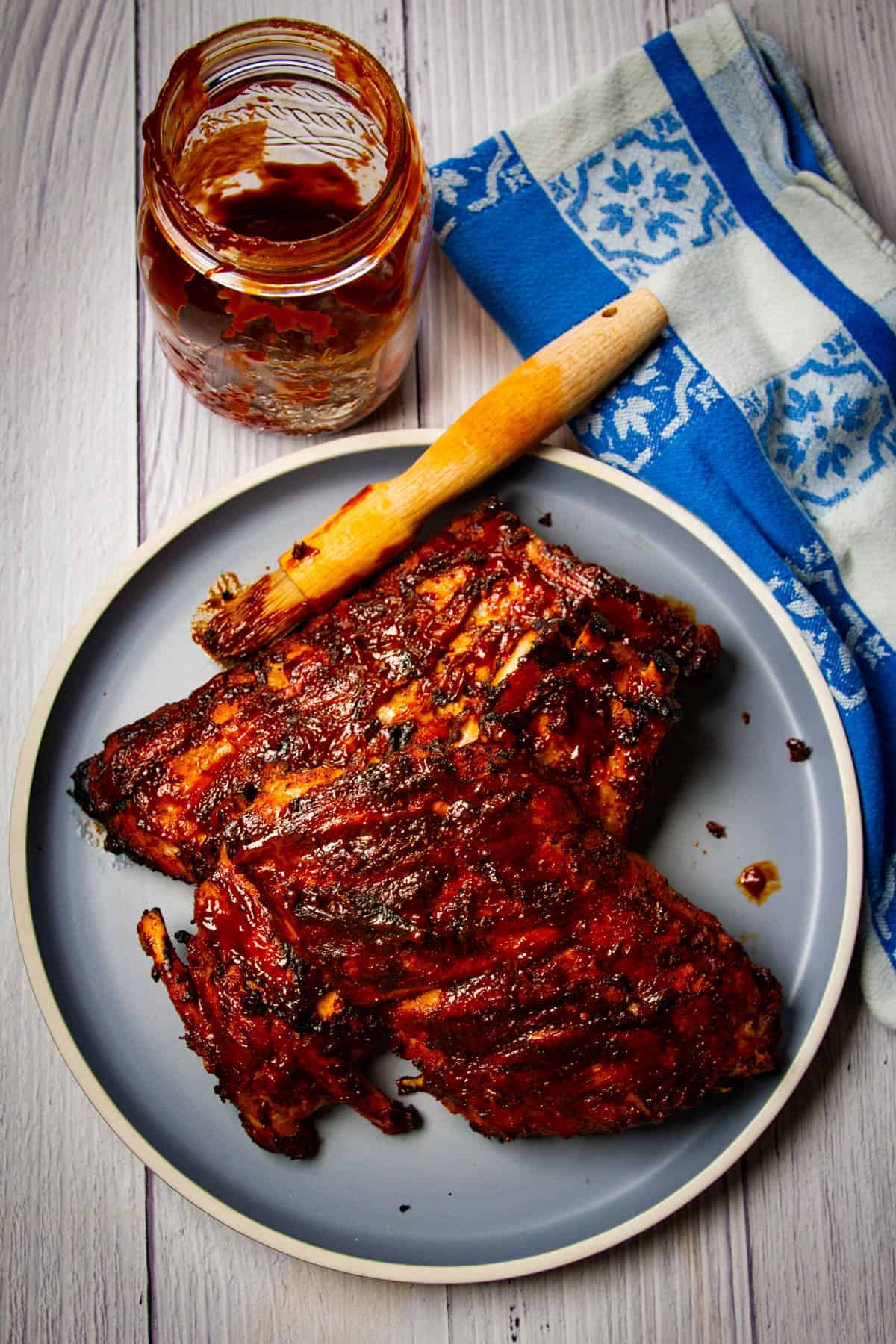 Fall off the bone ribs on a plate with a brush and some bbq sauce.