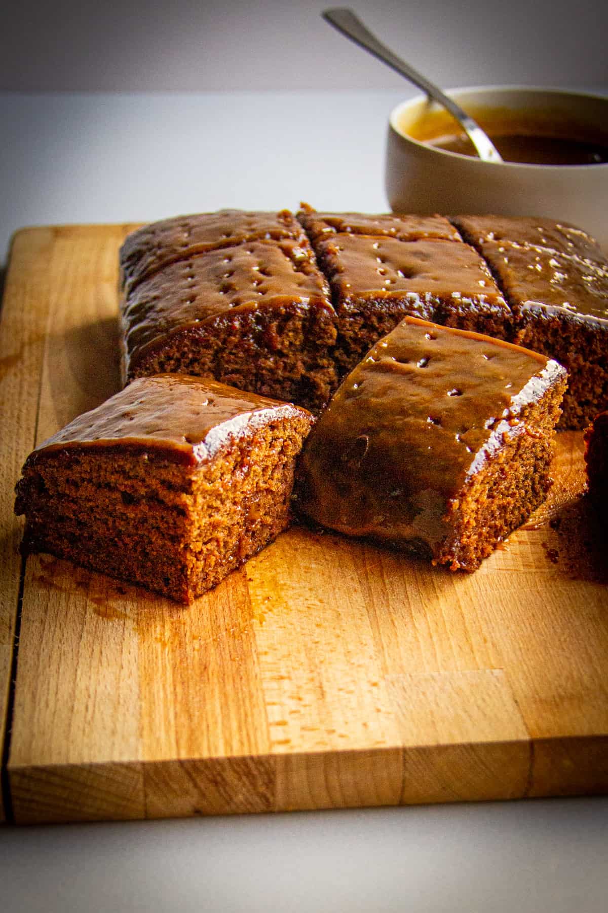 A close up of the sliced sticky toffee pudding on a wooden board.