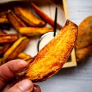 Crispy sweet potato wedges with spicy mayo in the background.