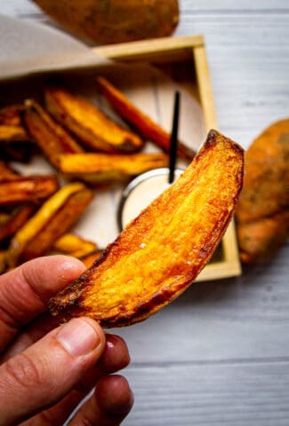 Crispy sweet potato wedges with spicy mayo in the background.