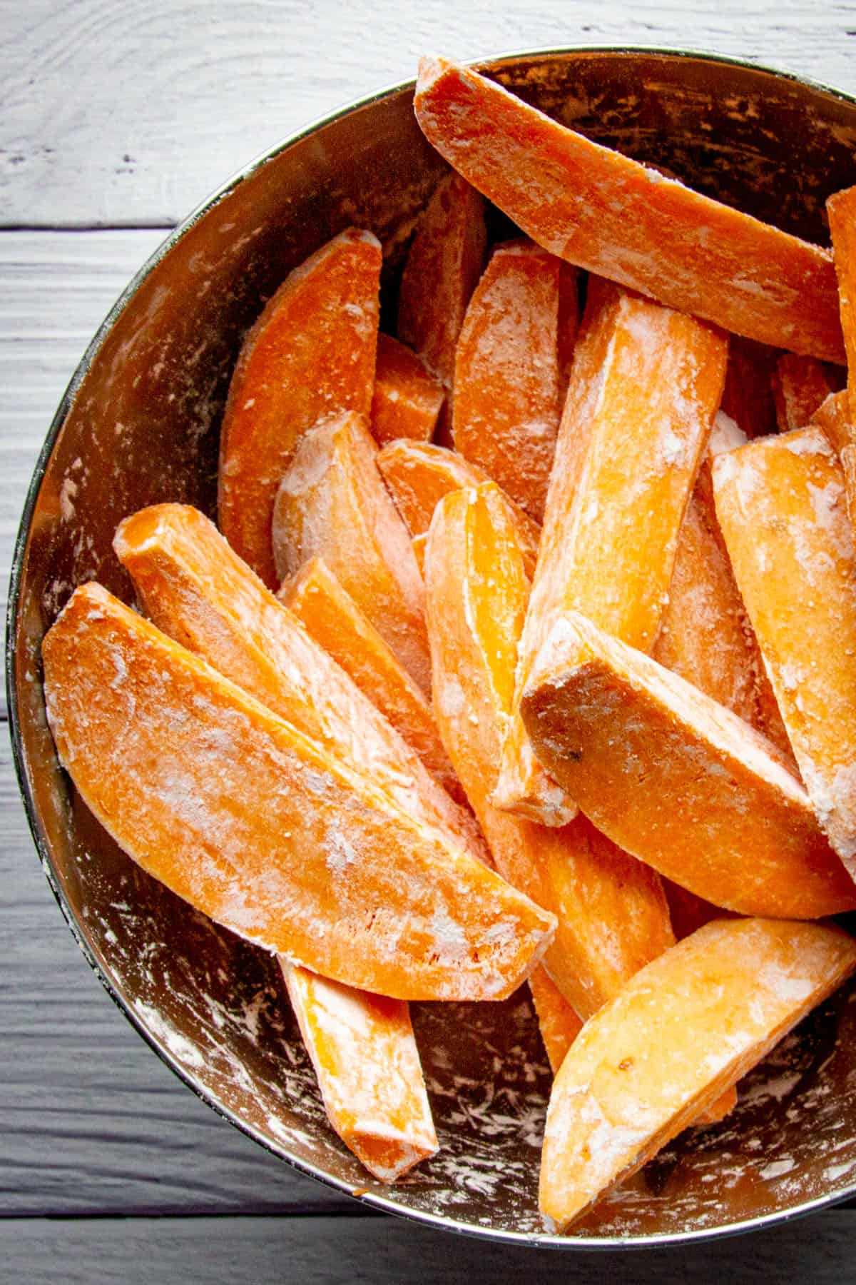 Raw wedges dredged in cornstarch in a bowl.