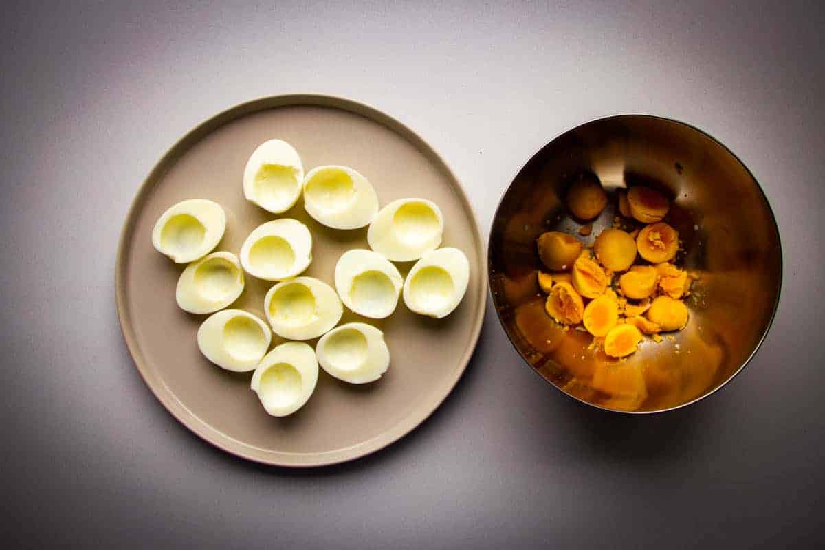 One bowl with hard boiled egg yolks and one with cooked egg whites.