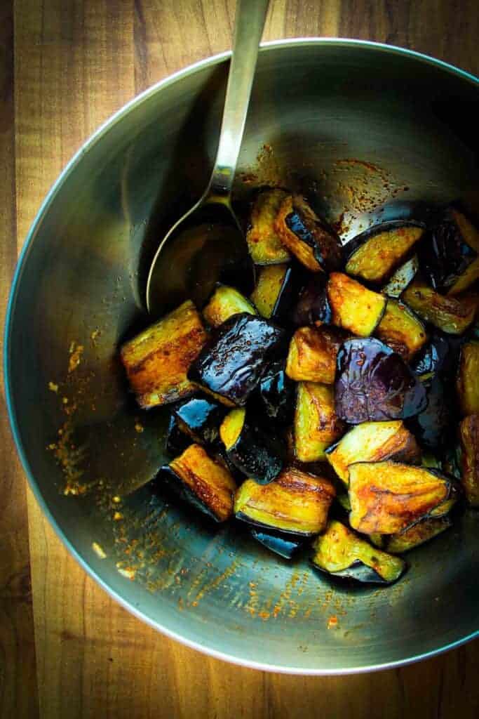 Mixing the fried eggplant in the bowl.