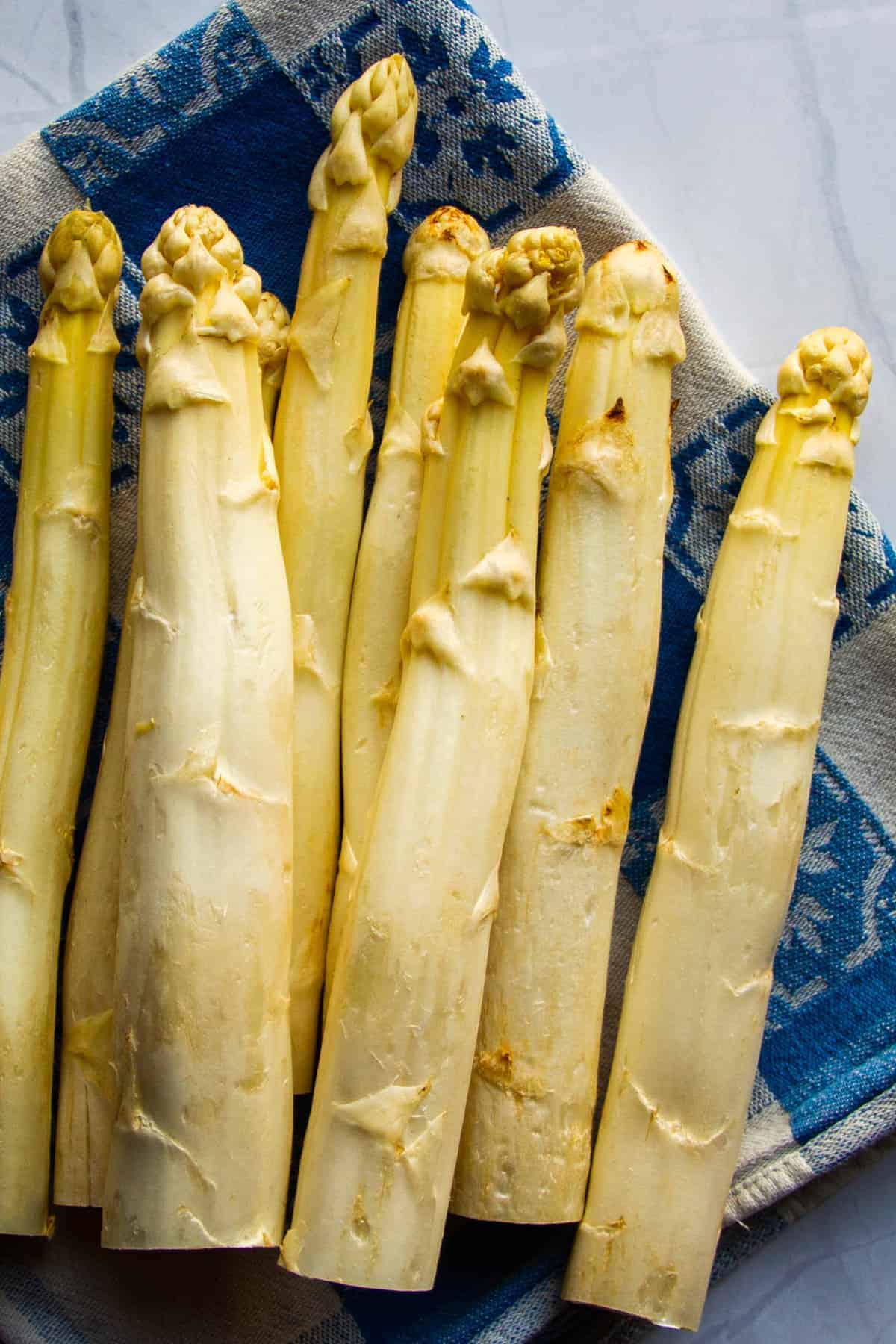 raw white asparagus on a blue towel.