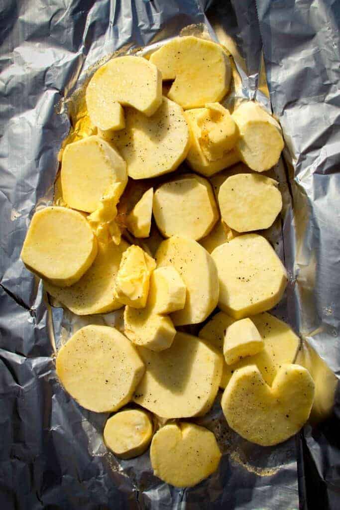 White sweet potatoes raw on foil with butter and salt.