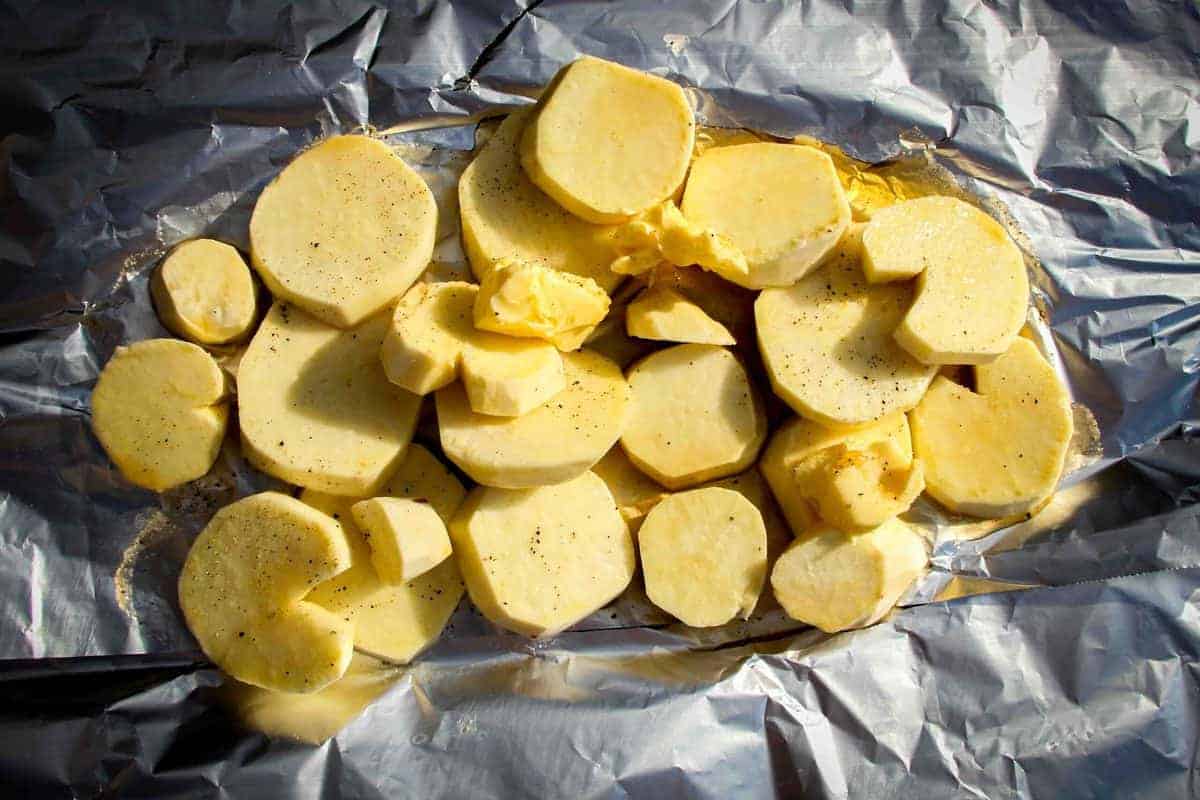 White sweet potatoes raw on foil with butter and salt.