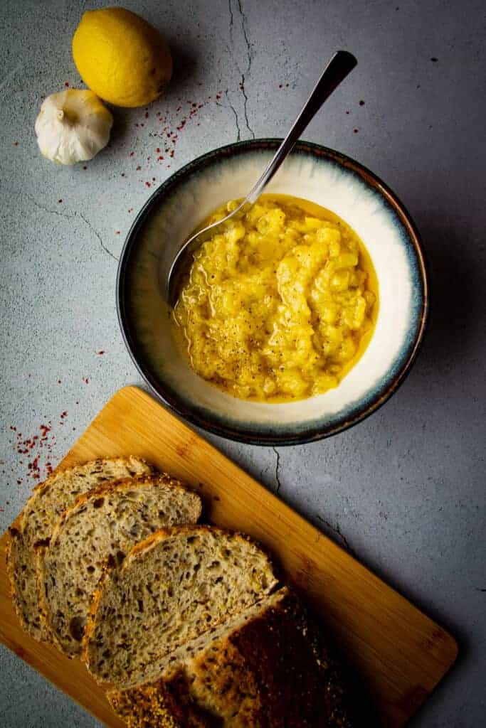 zucchini dip in a bowl with fresh bread on the side.