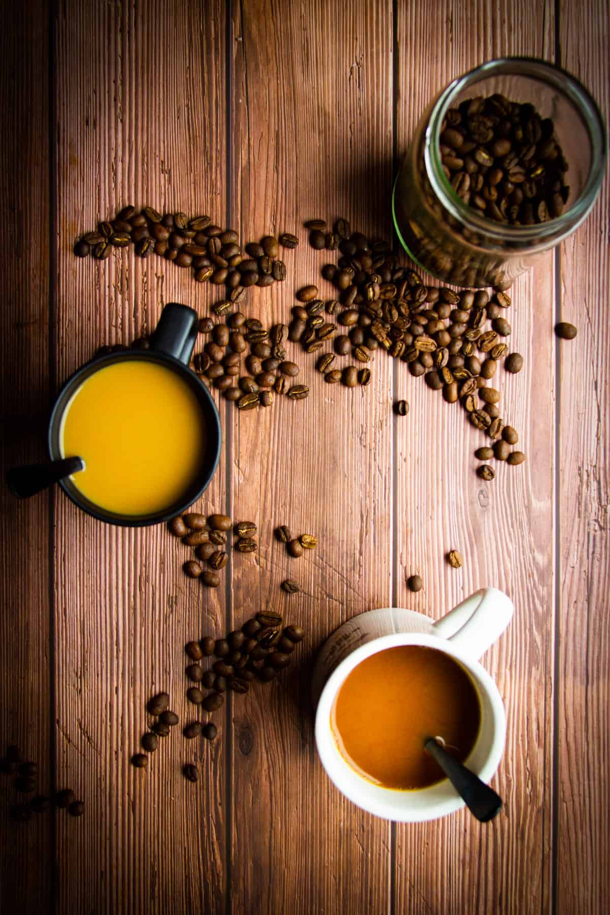 Two coffees on the table with some coffee beans.