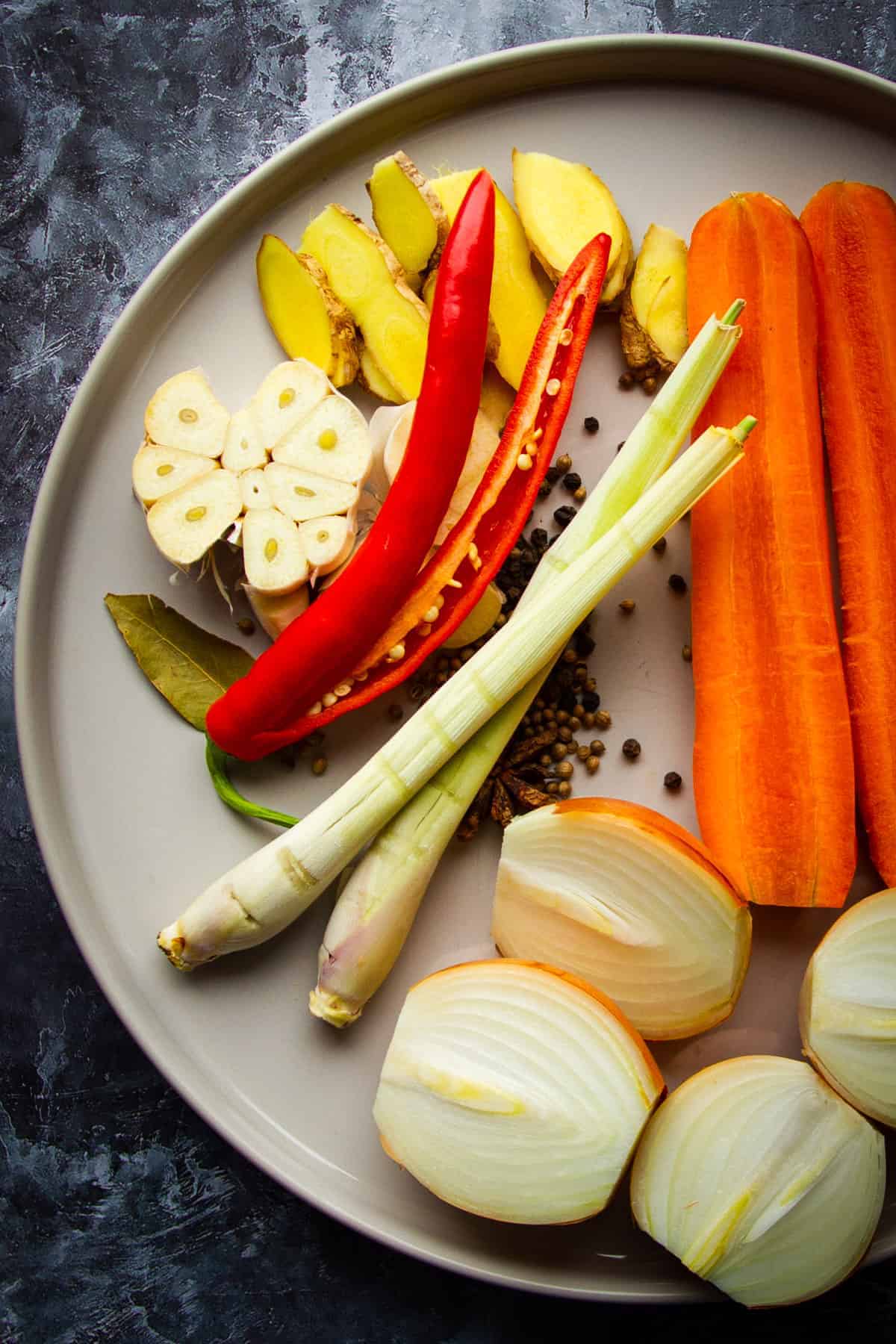 The vegetables and spices raw on a plate for the chicken bone broth.