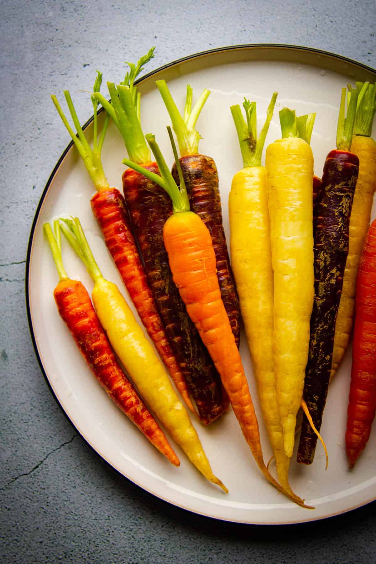 Raw rainbow carrots on a big plate, not peeled.