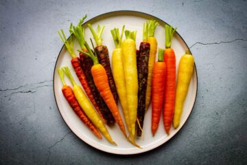 The raw rainbow carrots cleaned on a plate.
