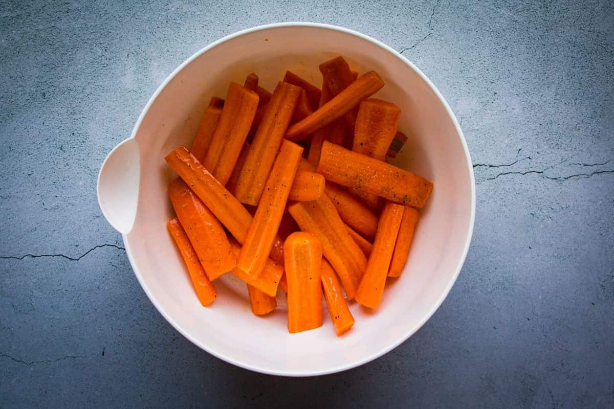 Tossing the carrots in bowl with salt, oil and pepper.