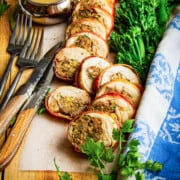 A close up of a stuffed chicken leg sliced on a board.