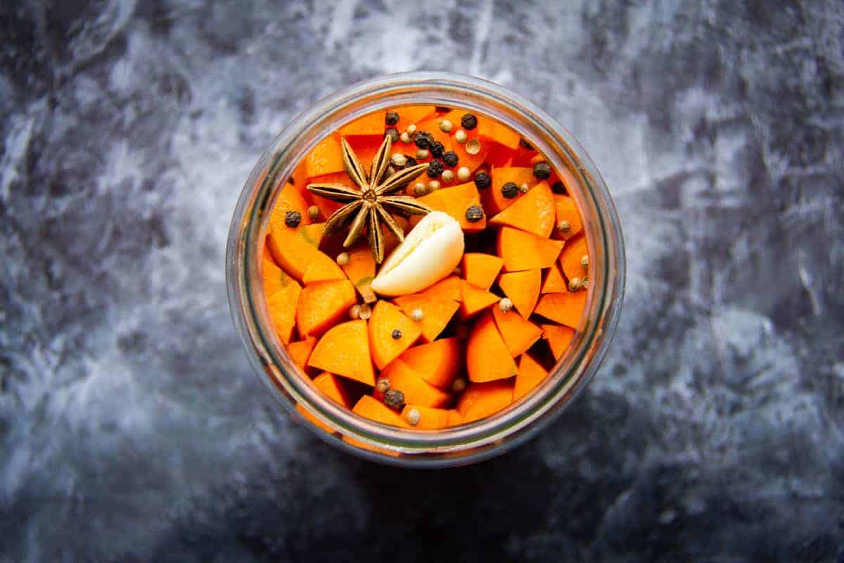 Fermented carrots in a mason jar with spices.