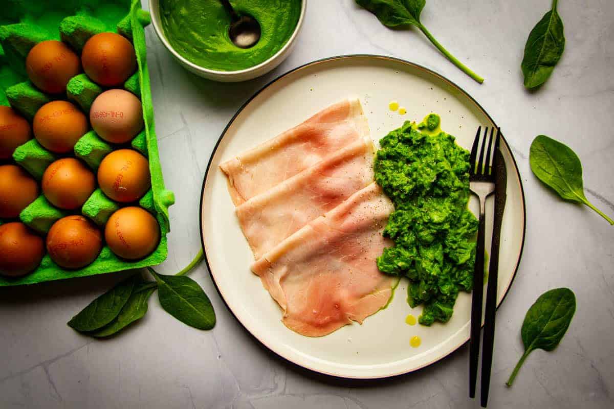 Green eggs and ham on a plate with a knife and fork.