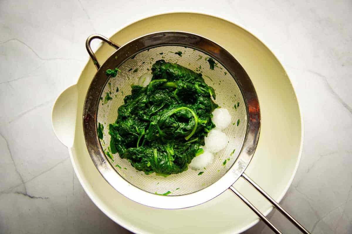 Straining the cooked spinach.